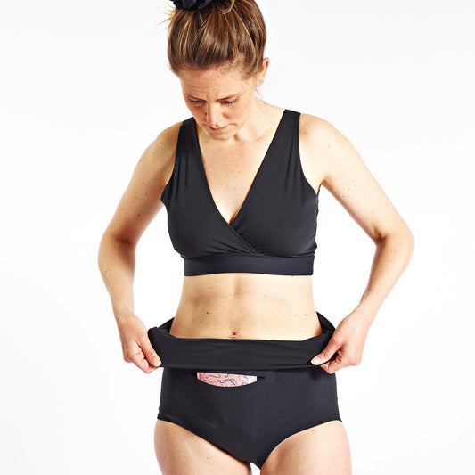 Image of woman folding the waist band over in her FourthWear Postpartum Recovery Underwear